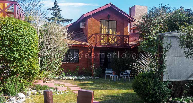 Parque con canteros y trepadoras. Cabañas de ladrillos visto madera y tejas