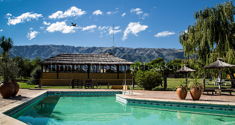 Piscina, quincho en segundo plano y sierras al fondo